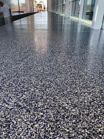 Blue and gray flake epoxy floor in a glass-walled walkway in Naples, FL