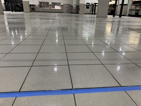 Glossy gray flake epoxy floor with a blue accent in a retail space in Naples, FL