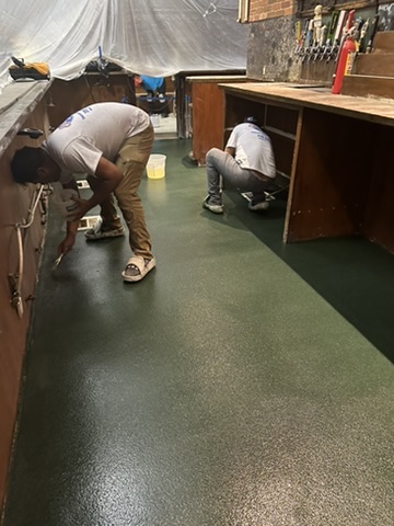 Dark green solid-color epoxy floor behind a bar in Naples, FL