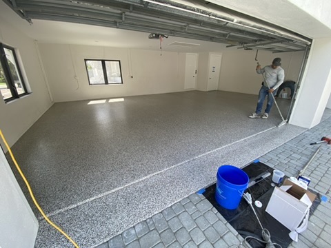 Two-car garage floor in a Cape Coral, FL home finished with a tan and gray flake coating and sealed edges