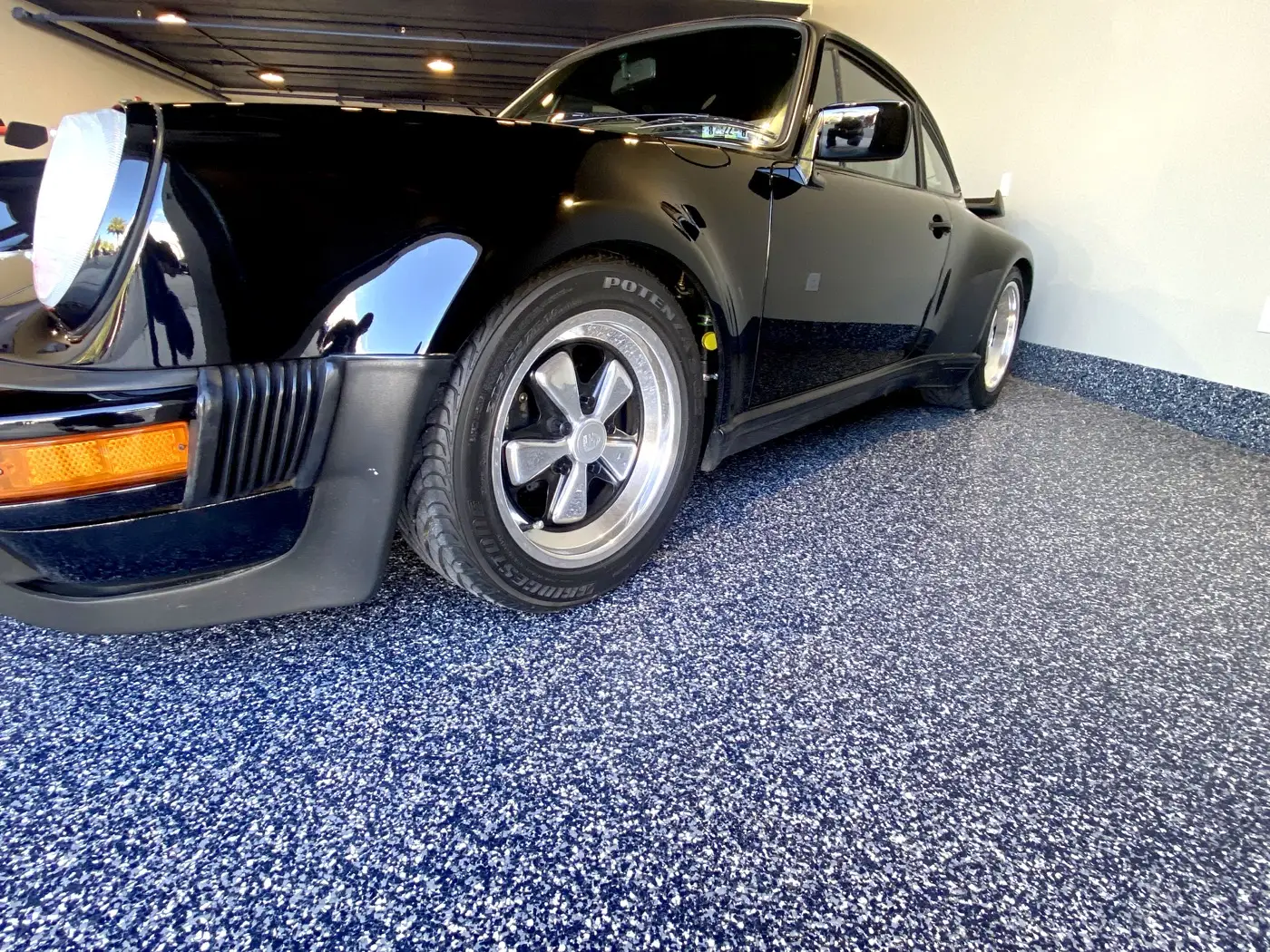 Black Porsche 911 on dark blue flake epoxy garage floor