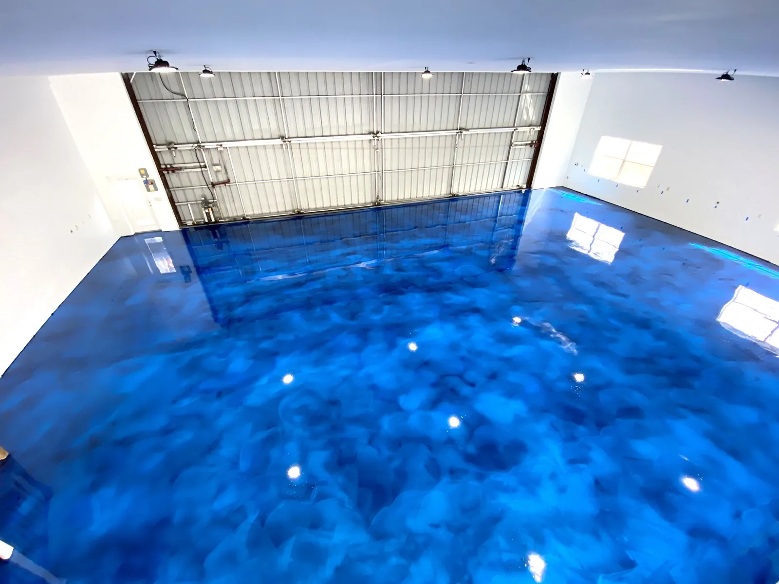 Deep blue metallic epoxy floor finished in a Cape Coral, FL garage set up as a home gym